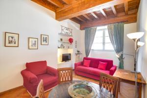 un soggiorno con 2 sedie rosse e un tavolo di Mamo Florence - Palazzo Spinelli Apartment a Firenze