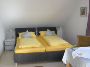 Schlafzimmer mit einem Bett mit gelber Bettwäsche und Kissen in der Unterkunft Ferienwohnung am Bodensee in Uhldingen-Mühlhofen