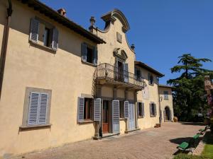 een oud gebouw met een balkon en ramen met luiken bij Villa di Cabbiavoli in Castelfiorentino
