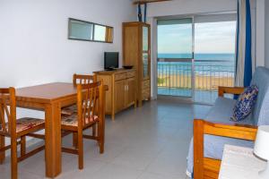 a living room with a dining room table and a balcony at Irtaplaya 310 in Alcossebre