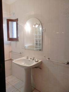 a white bathroom with a sink and a mirror at Casa das Palmeiras in Aljezur