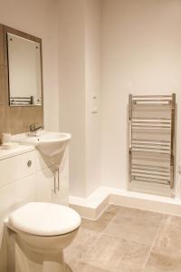 a white bathroom with a toilet and a sink at Luxury Apartments Newcastle in Newcastle upon Tyne