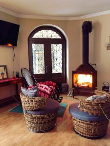 a living room with a fireplace and wicker ottomans and a fire at Family Hotel Kala in Mestia