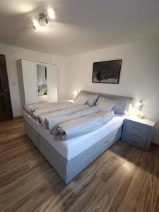 a large white bed in a bedroom with wooden floors at Appartment Fuzzy in Sölden