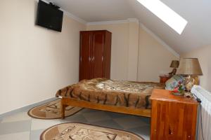 1 dormitorio con 1 cama y TV en la pared en Лелека, en Dilyatyn