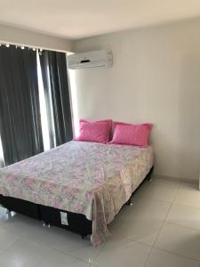a bedroom with a bed with pink pillows at Edf. Dom João in São José da Coroa Grande
