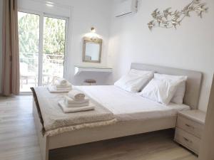 a white bedroom with a large bed and a window at Sea Breeze Villa in Haraki