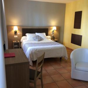 a bedroom with a bed and a desk and a chair at Logis Hotel De L'Etang in Cucuron