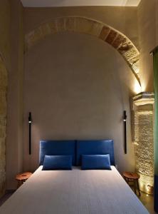 a bed with two blue pillows in a room at Chiostro di S. Antonio in Marsala