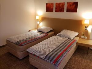two beds in a hotel room with two tables at Noclegi Portowa in Opole