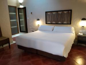 Beach Hotel Dos Mares في تريفة: سرير أبيض كبير في غرفة بها مصباحين