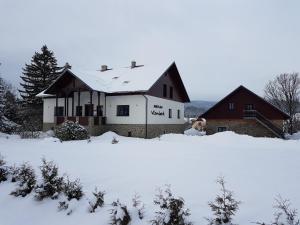 una casa con nieve en el suelo delante de ella en Apartmány Vízmberk, en Velké Losiny