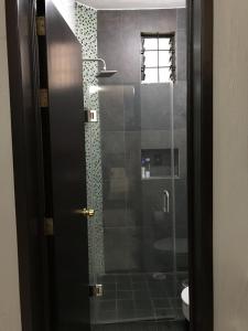 La salle de bains est pourvue d'une douche avec une porte en verre. dans l'établissement Preciados Loft Cold AC best WIFI, à Tequila