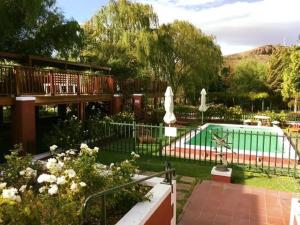 a pool in a yard with a fence and flowers at Beaufort Manor Country Lodge in Beaufort West