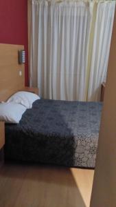 Cama en habitación de hotel con ventana en Guest House Estrela, en Oporto