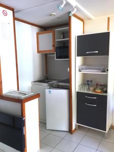 Il comprend une petite cuisine équipée d'un réfrigérateur blanc et d'une cuisinière. dans l'établissement CHALET 407 KHELUS-CLUB, à Gujan-Mestras