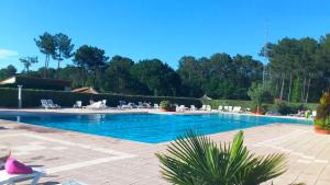 une grande piscine avec des personnes assises autour de celle-ci dans l'établissement CHALET 407 KHELUS-CLUB, à Gujan-Mestras