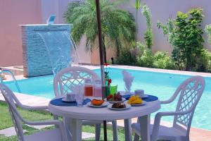 a table with food on it next to a pool at Villa Araçà - Boutique Hotel in Lauro de Freitas