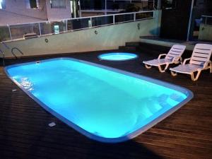 una gran piscina con 2 tumbonas en Residencial Lorenzi, en Florianópolis