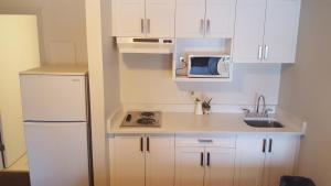 uma pequena cozinha com armários brancos e um micro-ondas em Chateau Motel em Edmonton