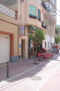 a street with red tables and chairs in front of a building at Hostal Juventus in Portbou