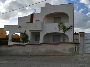 a white building with a palm tree in front of it at Villa Isolde in Triscina