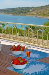 una mesa con dos tazones de fruta y copas de vino en Casa Baia Tramonto, en Patù