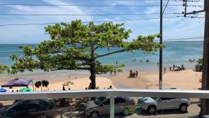 Apartamento 3 quartos Beira Mar في أنشيتا: شاطئ فيه شجرة وناس في الماء