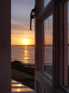 een uitzicht vanuit een raam op een zonsondergang bij Stella Maris Shore House in Ballycastle