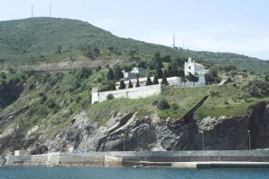 a house on the side of a hill next to the water at Hostal Juventus in Portbou