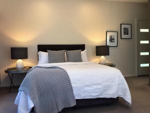 a bedroom with a large white bed with two lamps at Daylesford Spa Villa One in Daylesford