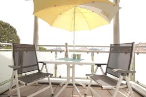 ホールマージールにあるStrandgutのテーブルと椅子2脚、黄色い傘