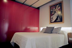 a bedroom with a white bed with red walls at Loft Bordador in Seville