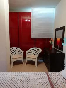 a bedroom with two white chairs and a red wall at Sole&Mare in Monopoli