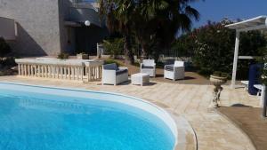 a swimming pool with white chairs and a table at Sole&Mare in Monopoli