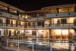 - un grand bâtiment avec une piscine la nuit dans l'établissement El Virrey Hotel Boutique, à Honda