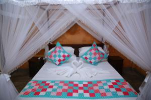 a bed with a checkered blanket and pillows in a tent at Limecabanas-srilanka in Galle