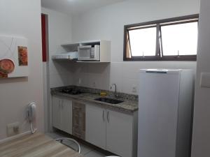 a small kitchen with a sink and a microwave at Aldeia do Lago C104- Churrasqueira, bebidas liberadas nas piscinas, internet no ap, rampa no lago, pesqueiro, carregador carro elétrico in Caldas Novas
