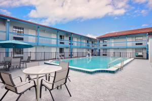 un patio con mesa, sillas y piscina en Baymont by Wyndham Jacksonville Orange Park, en Jacksonville