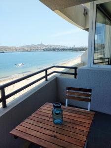 un banco de madera en un balcón con vistas a la playa en Departamento La Herradura, Coquimbo, en Coquimbo