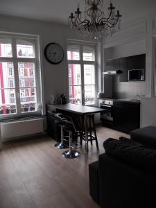 a living room with a table and a clock on the wall at Nationale Appart Hotel in Lille