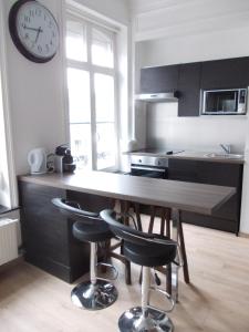 une cuisine avec une table en bois et une horloge murale dans l'établissement Nationale Appart Hotel, à Lille