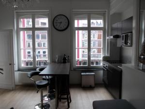 a kitchen with two windows and a clock on the wall at Nationale Appart Hotel in Lille