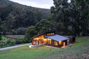 uma casa numa colina com as luzes acesas em Adventure Bay Retreat Bruny Island em Adventure Bay