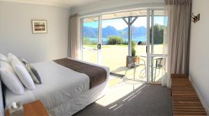 a bedroom with a bed and a balcony with a view at Collingwood Park Motel in Collingwood