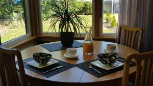drewniany stół z dwoma kubkami i wazonem soku pomarańczowego w obiekcie Morning Bloom Cottage Bed and Breakfast w mieście Nelson