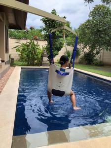 a person in a swing in a swimming pool at Accessible Penyaringan in Sanur