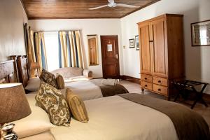 a bedroom with two beds and a dresser at Matoppo Inn in Beaufort West