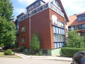 a red brick building with a tree in front of it at Apartamentai Taikos 24 in Nida