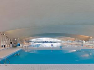 a large swimming pool with blue water in a building at LE COEUR DE DEAUVILLE - 2 PIECES DESIGN EN HYPERCENTRE DE DEAUVILLE in Deauville